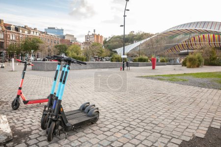 Téléchargez les photos : Panorama d'une rue liégeoise avec scooters électriques sans quai à louer, en Belgique, offrant une solution de mobilité urbaine écologique, pratique et moderne pour un transport personnel rapide et accessible. - en image libre de droit
