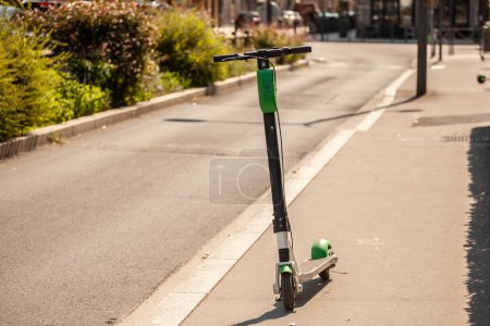 Téléchargez les photos : Flou sélectif sur un scooter électrique noir et vert à louer, disponible dans les rues de Lyon, France, autonome, appartenant à une entreprise technologique spécialisée dans le partage de véhicules. - en image libre de droit