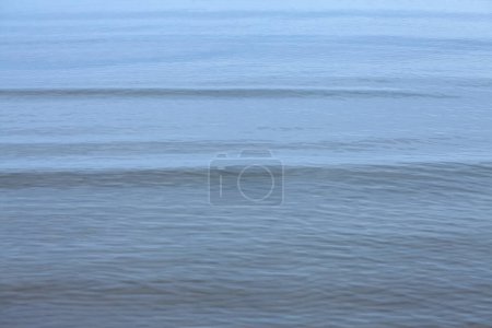 Foto de Desenfoque selectivo en pequeñas olas en las aguas del mar Báltico durante un clima neblinoso y una tarde lluviosa en la playa de Jurmala (Jurmalas Pludmale) en Dubulti, Letonia. - Imagen libre de derechos