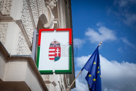 Ungarisches Wappen vor einer Flagge der Europäischen Union in der ungarischen Stadt Pecs. Ungarn ist seit 2004 Mitglied der EU und ein wichtiger Akteur des europäischen Spiels.