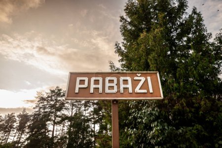 Selektive Unschärfe auf einem Schild, das den Eingang zu Pabazi in der Abenddämmerung in einem typischen Ostseewald anzeigt. Pabazi ist eine lettische Stadt, ein Badeort an der Ostseeküste Lettlands.