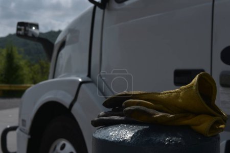 Téléchargez les photos : A symbol of the hardworking trucker, resting gloves on a semi truck at a mid-America gas station refueling stop - en image libre de droit