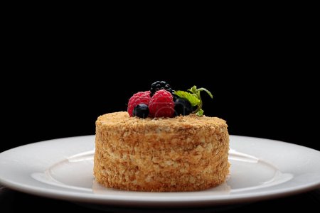 Téléchargez les photos : Napoleon cake with berries and mint, on a plate, on a black background - en image libre de droit