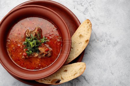 Photo for Georgian soup Kharcho with meat in a clay pot with bread - Royalty Free Image