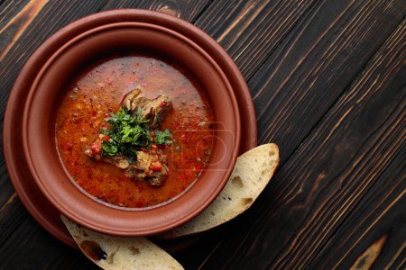 Foto de Georgian soup Kharcho with meat in a clay pot with bread - Imagen libre de derechos