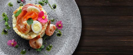 Téléchargez les photos : Olivier salad with shrimp, salmon and quail eggs on a plate, on a wooden background. Banner - en image libre de droit