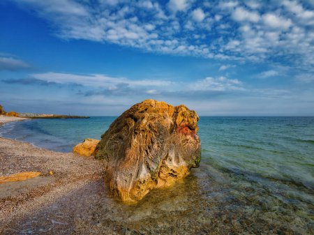 Photo for Big old stone on the seashore in sunny weather, blue sky and white clouds - Royalty Free Image
