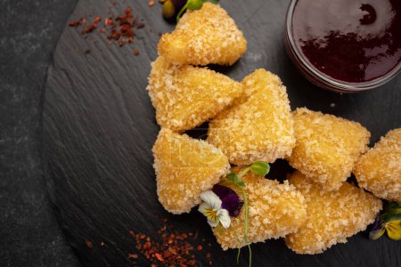 golden cheese nuggets on slate with sweet sauce