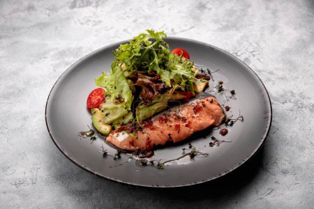 Photo for Perfectly cooked salmon fillet with vegetables and a side of salad mix. On a light background - Royalty Free Image