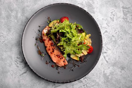 Foto de Filete de salmón perfectamente cocido con verduras y un lado de la mezcla de ensaladas. Sobre un fondo claro - Imagen libre de derechos