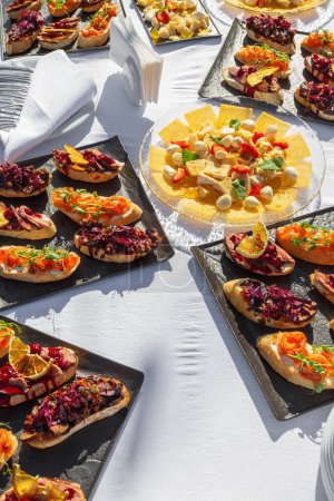 Photo for Bruschetta in assortment at outdoor catering on a white tablecloth - Royalty Free Image