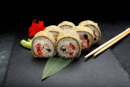 Téléchargez les photos : Rouleau de sushi chaud au thon sur une pierre noire au gingembre et wasabi - en image libre de droit