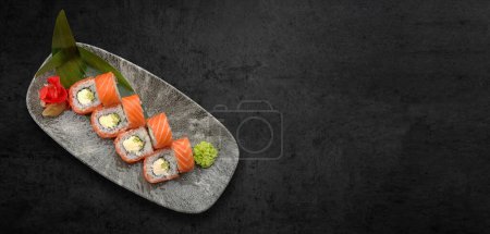 Klassisches Sushi-Brötchen mit Meeresfrüchten, Sojasauce, Wasabi und Ingwer. dunkler Hintergrund, horizontales Banner