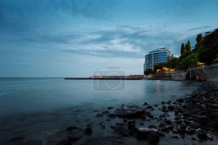 Téléchargez les photos : Soirée plage de rochers, bord de mer, hôtel longue exposition - en image libre de droit