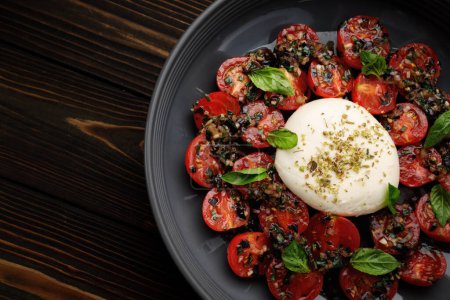 Burrata with baked cherry tomatoes and spices, on a plate