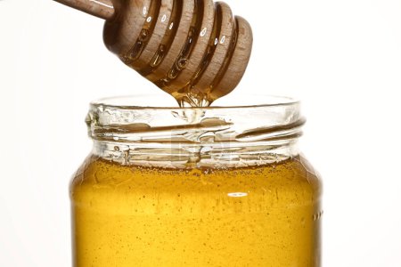 Foto de Tarro con miel de acacia y cuchara de madera de cerca - Imagen libre de derechos