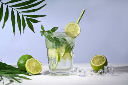 Téléchargez les photos : Verre avec cocktail mojito et citrons verts sur fond bleu - en image libre de droit
