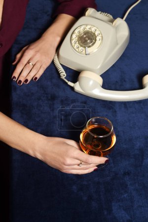 Téléchargez les photos : Main féminine avec verre de cognac et téléphone vintage - en image libre de droit