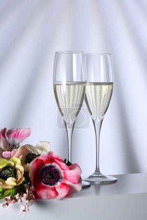 Téléchargez les photos : Deux verres avec champagne et fleurs sur fond illuminé - en image libre de droit