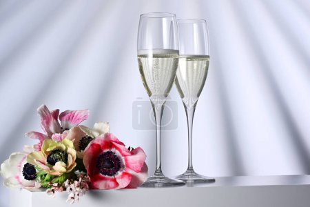 Téléchargez les photos : Deux verres avec champagne et fleurs sur fond illuminé - en image libre de droit