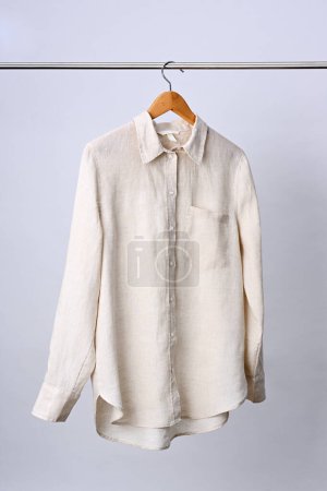Téléchargez les photos : Chemise en lin beige accrochée au cintre en bois - en image libre de droit