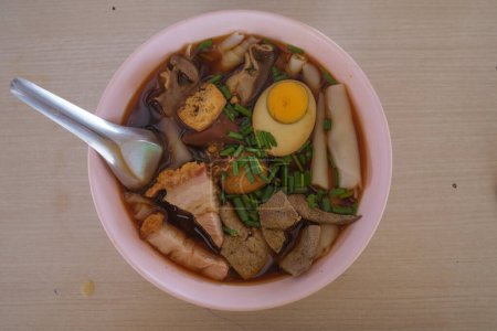 Soupe chinoise de nouilles roulées avec des ?ufs durs et du porc croustillant dans un bol blanc. c'est l'un des meilleurs thaïlandais Street Food
