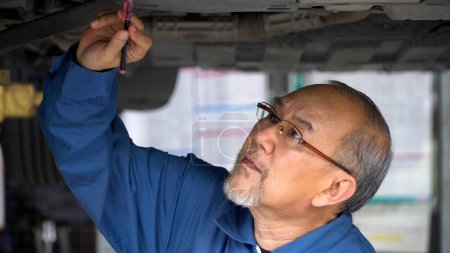 Téléchargez les photos : Senior asiatique mécanicien de voiture homme sous contrôle de voiture et en utilisant la réparation de clé dans le garage. old asia Mécanicien automatique de travail . - en image libre de droit