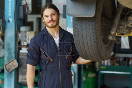 Photo for Mechanic worker checking car replacing car wheel and tyre in auto repair shop store service. worker maintenance examining and installing wheel tire at garage. - Royalty Free Image