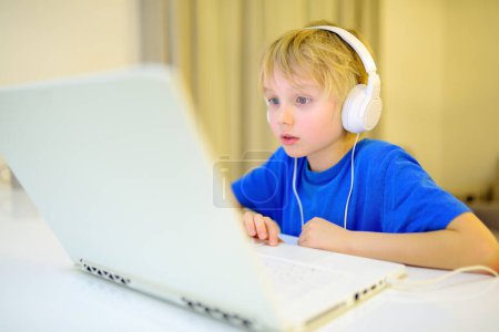 Schüler nutzen die Computer-App zum Lernen mit dem Laptop zu Hause. Kind schaut Film. Kind und Gadgets. Kleine Kinder mit moderner Technik. Online-Bildung und Fernunterricht für Kinder.