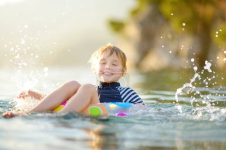 Little boy swimming with colorful floating ring in sea on sunny summer day. Cute child playing in clean water. Family and kids resort holiday during summer vacations. Resting and relaxation by sea.