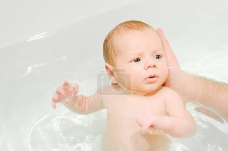 Téléchargez les photos : Un jeune père baigne son nouveau-né. Parentalité. Impliqué papa prendre soin de son fils en bas âge - en image libre de droit