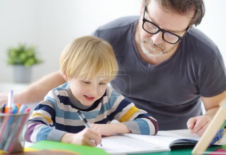 Photo for Father helping child do his homework at home. Raising hyperactive children is a problem for parents.Tutor teaching boy with ADHD. - Royalty Free Image