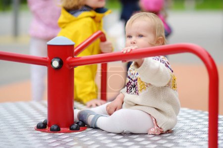 Photo for Toddler girl having fun on outdoor playground. Preschooler brother rides younger sister on carousel. Friendship of siblings. Spring/summer/autumn active sport leisure for kids. Activities for children - Royalty Free Image