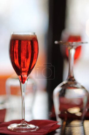 Téléchargez les photos : Vue verticale du verre avec boisson alcoolisée française Kir Royal sur la table du restaurant - en image libre de droit