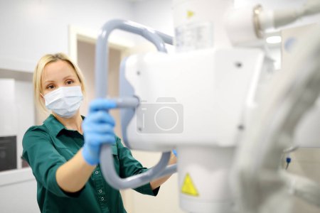 Technikerin justiert Röntgengerät. Die Radiologin wird eine Röntgenaufnahme der Patientin im Röntgenraum der modernen Klinik machen. Medizinische Untersuchung von Personen