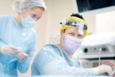 Téléchargez les photos : Les chirurgiens sont pendant l'opération maxillofaciale en utilisant le microscope et l'endoscope dans l'hôpital moderne. Travail d'équipe de médecins en salle d'opération. Chirurgie maxillofaciale. - en image libre de droit