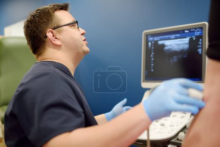 Photo for Professional vascular surgeon making ultrasound of the vein of patient in clinic before vein surgery. Phlebectomy. Professional doctors during consultation about endovascular vein surgery operation - Royalty Free Image