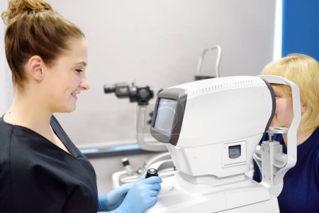 Foto de Examen del fondo de la mujer madura por oftalmóloga usando escáner de retina. Paciente durante la visita al optometrista para análisis microscópico de párpados, esclerótica, conjuntiva, iris, lente, córnea. - Imagen libre de derechos