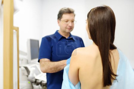 Doctor mammologist examines woman breasts. Correcting the shape of the breast - lift, reduction, reconstruction, augmentation. Problems of lactation. Breast cancer awareness
