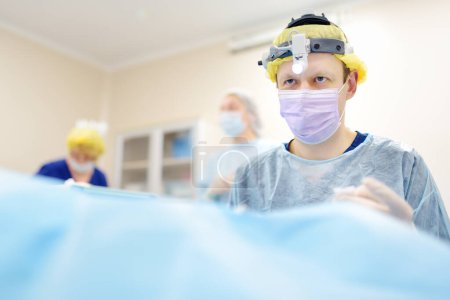 Les chirurgiens sont pendant l'opération maxillofaciale en utilisant le microscope et l'endoscope dans l'hôpital moderne. Travail d'équipe de médecins en salle d'opération. Chirurgie maxillofaciale.