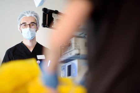 Un stagiaire assistant surveille l'état du patient pendant la chirurgie en salle d'opération dans un hôpital médical moderne.