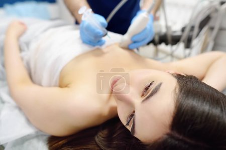 Photo for Mammalogist doctor examines a woman breasts and lymph nodes during appointment. Skillful oncologist puncture of mammary glands of young patient under review ultrasound for diagnosis of breast cancer. - Royalty Free Image
