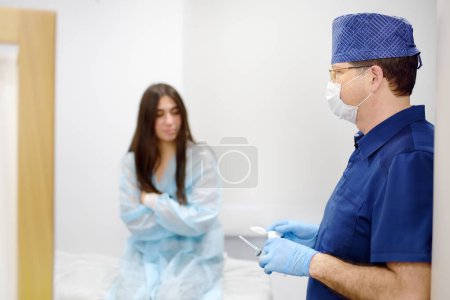 Mammalogist doctor is preparing to examine woman breasts and lymph nodes using ultrasound for diagnosis of breast cancer during appointment. Oncologist holding hands biopsy slide glasses and syringe.