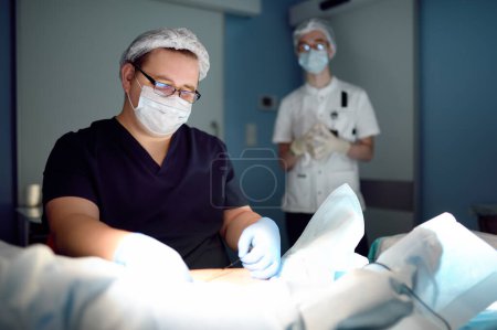Professional vascular surgeon and assistant in the operating room of the clinic during vein surgery. Phlebectomy. A team of professional doctors during their work in the operating room. DVT