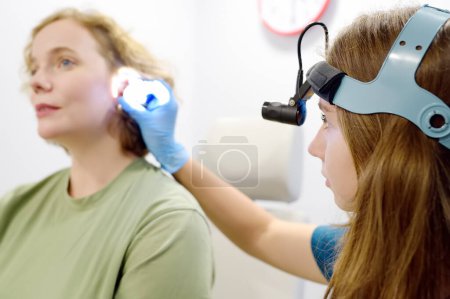 Foto de Un paciente es atendido por un otorrinolaringólogo. Un médico otorrinolaringólogo profesional examina a un paciente. Un otorrinolaringólogo examina el oído interno de un paciente usando un otoscopio. El tratamiento de la inflamación de los oídos. - Imagen libre de derechos