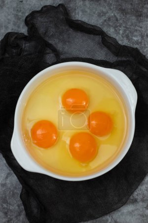 Photo for Few yellow egg yolks in a white bowl on dark - Royalty Free Image