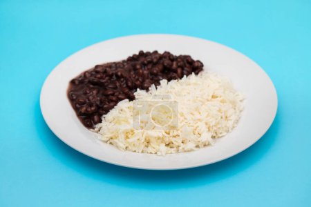 Schwarze Bohnen und gekochter Reis auf weißem Teller.