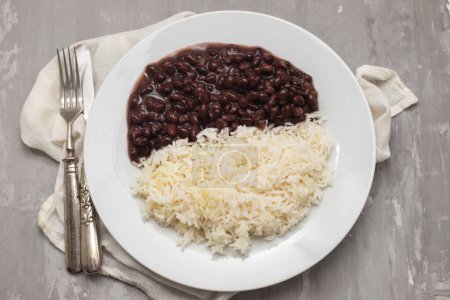 Schwarze Bohnen und gekochter Reis auf weißem Teller.