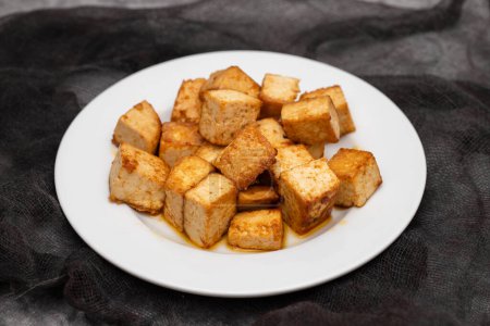 crispy deep stir fried tofu cubes on small white dish