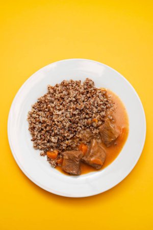 Photo for Boiled buckwheat with meat and sauce on white big dish - Royalty Free Image